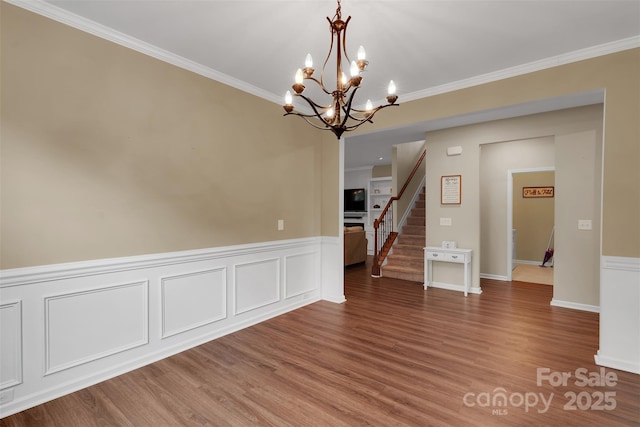 417 Brier Knob Dr, Fort Mill, SC 29715 - unfurnished dining area featuring a chandelier, a wainscoted wall, crown molding, wood finished floors, and stairway