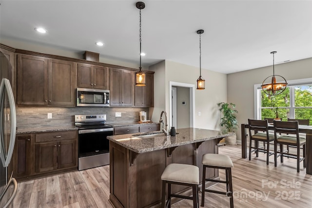 552 High Trail Dr, Nebo, NC 28761 - kitchen with stainless steel appliances, light wood finished floors, decorative backsplash, dark brown cabinets, and a kitchen bar
