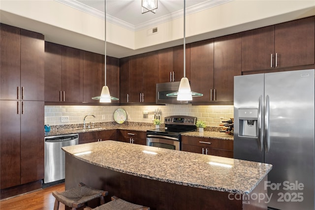 4620 Piedmont Row Dr Unit 308, Charlotte, NC 28210 - kitchen with appliances with stainless steel finishes, ornamental molding, a kitchen breakfast bar, light stone counters, and backsplash