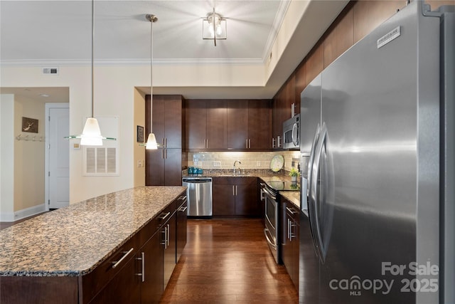 4620 Piedmont Row Dr Unit 308, Charlotte, NC 28210 - kitchen featuring appliances with stainless steel finishes, a kitchen island, tasteful backsplash, crown molding, and dark wood finished floors