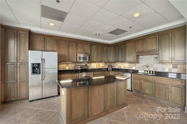4620 Piedmont Row Dr Unit 308, Charlotte, NC 28210 - kitchen featuring stainless steel appliances, a sink, a kitchen island, decorative backsplash, and a paneled ceiling