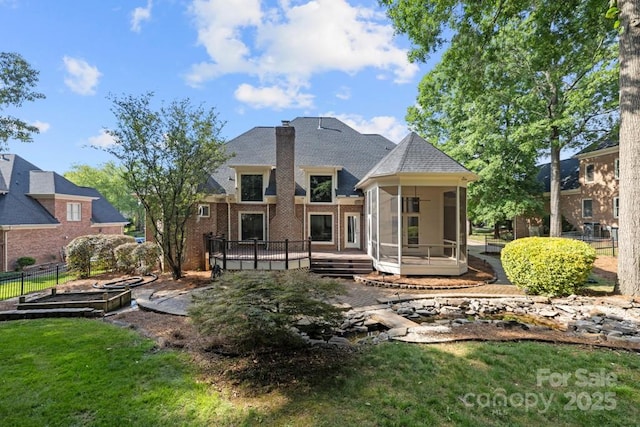 9219 Whispering Wind Dr, Charlotte, NC 28277 - rear view of property with a sunroom, a deck, brick siding, a shingled roof, and a chimney