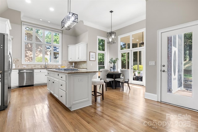 9219 Whispering Wind Dr, Charlotte, NC 28277 - kitchen featuring stainless steel appliances, white cabinets, a kitchen bar, a kitchen island, and decorative backsplash