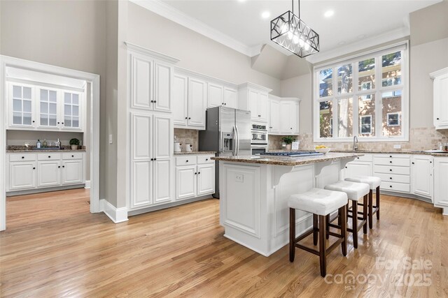 9219 Whispering Wind Dr, Charlotte, NC 28277 - kitchen with stainless steel appliances, tasteful backsplash, white cabinetry, a kitchen bar, and a kitchen island