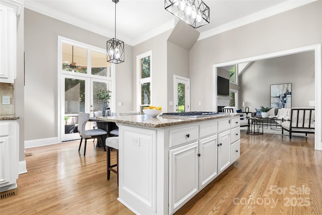 9219 Whispering Wind Dr, Charlotte, NC 28277 - kitchen with crown molding, a chandelier, light wood-type flooring, white cabinetry, and light stone counters