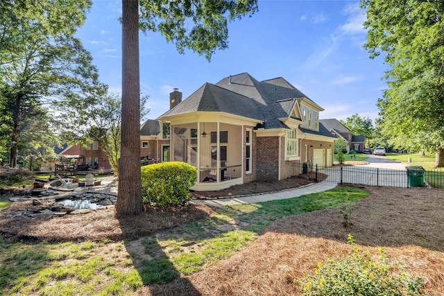 9219 Whispering Wind Dr, Charlotte, NC 28277 - rear view of house featuring a sunroom, brick siding, an attached garage, a shingled roof, and a chimney