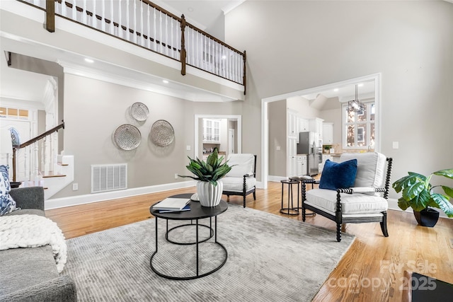 9219 Whispering Wind Dr, Charlotte, NC 28277 - living area featuring a towering ceiling, baseboards, light wood-style flooring, stairs, and ornamental molding