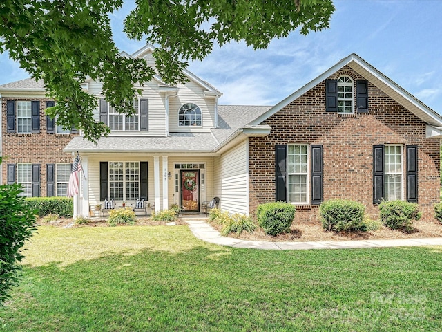 1109 Woodwinds Dr, Waxhaw, NC 28173 - traditional-style home with covered porch, a front yard, brick siding, and a shingled roof