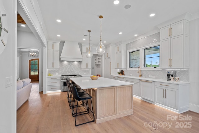1405 Waxhaw Marvin Rd, Waxhaw, NC 28173 - kitchen featuring high end range, wall chimney range hood, decorative backsplash, light countertops, and a breakfast bar