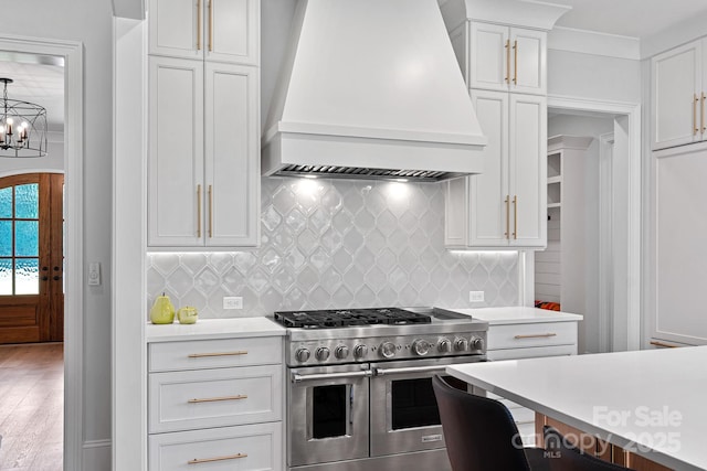 1405 Waxhaw Marvin Rd, Waxhaw, NC 28173 - kitchen with range with two ovens, wall chimney range hood, light countertops, white cabinetry, and a chandelier