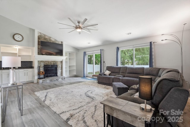 3807 Sweetgrass Ln, Charlotte, NC 28226 - living area featuring light wood-style flooring, ceiling fan, a stone fireplace, and lofted ceiling