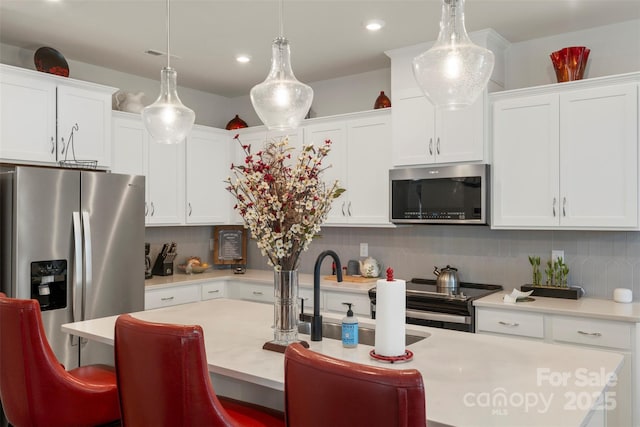 13327 Savaine St, Charlotte, NC 28278 - kitchen featuring stainless steel appliances, light countertops, a kitchen bar, white cabinets, and an island with sink
