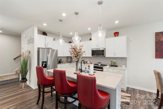 13327 Savaine St, Charlotte, NC 28278 - kitchen featuring appliances with stainless steel finishes, light countertops, dark wood-style floors, decorative backsplash, and a kitchen island with sink