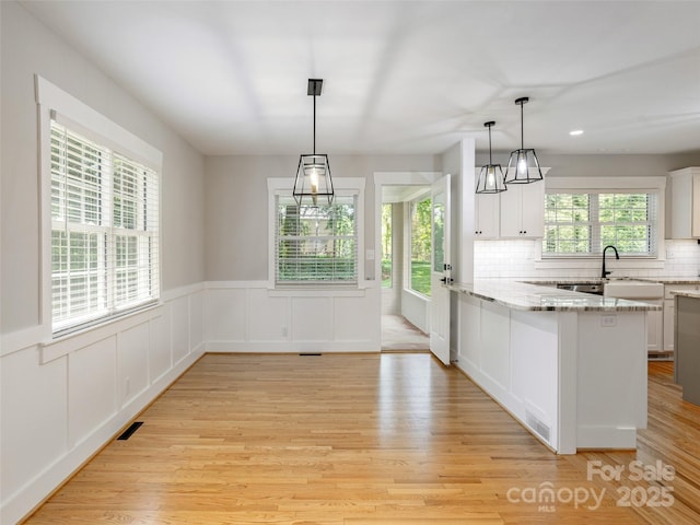 330 Balsam Rd, Hendersonville, NC 28792 - kitchen with light wood-style flooring, a peninsula, white cabinetry, light stone counters, and a wainscoted wall
