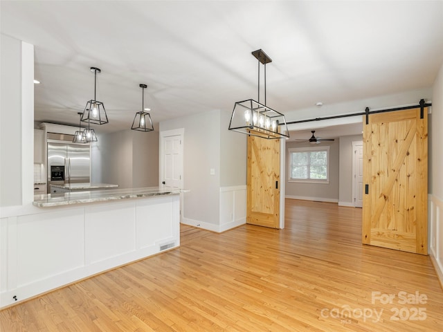 330 Balsam Rd, Hendersonville, NC 28792 - kitchen featuring built in refrigerator, a barn door, light wood-style flooring, a peninsula, and wainscoting