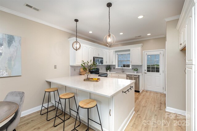 121 Quality Dr, Mount Holly, NC 28120 - kitchen with appliances with stainless steel finishes, a sink, a peninsula, a kitchen breakfast bar, and light wood-type flooring