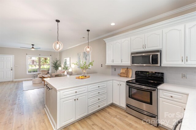 121 Quality Dr, Mount Holly, NC 28120 - kitchen featuring appliances with stainless steel finishes, a peninsula, light wood-style flooring, decorative backsplash, and crown molding
