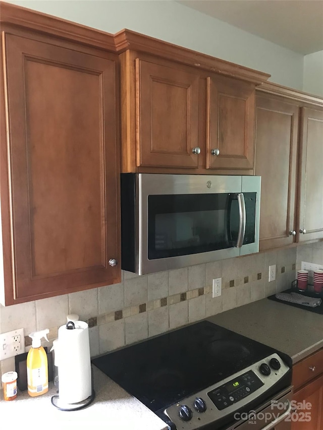 19157 Mallard Dr, Fort Mill, SC 29707 - kitchen view of appliances with stainless steel finishes, tasteful backsplash, and brown cabinetry