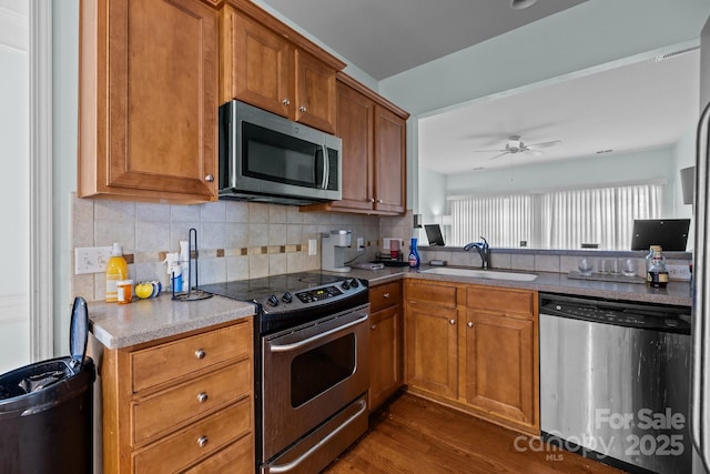 19157 Mallard Dr, Fort Mill, SC 29707 - kitchen with appliances with stainless steel finishes, a sink, dark wood-type flooring, brown cabinets, and decorative backsplash