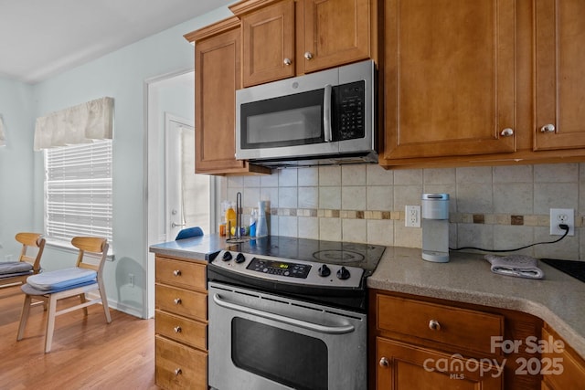 19157 Mallard Dr, Fort Mill, SC 29707 - kitchen with stainless steel appliances, brown cabinets, light wood-type flooring, and backsplash