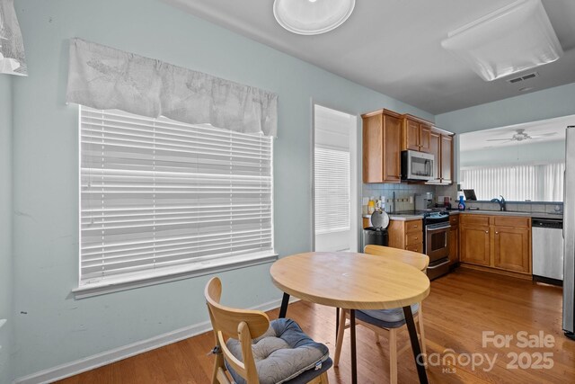 19157 Mallard Dr, Fort Mill, SC 29707 - kitchen with appliances with stainless steel finishes, wood finished floors, brown cabinetry, tasteful backsplash, and baseboards