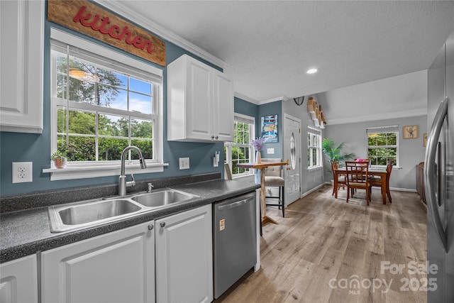 7830 Sarah Dr, Denver, NC 28037 - kitchen with stainless steel appliances, a sink, dark countertops, white cabinets, and crown molding