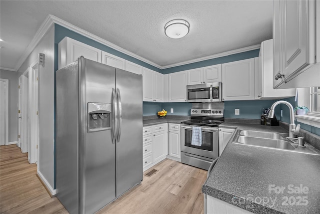 7830 Sarah Dr, Denver, NC 28037 - kitchen featuring stainless steel appliances, a sink, dark countertops, crown molding, and white cabinets