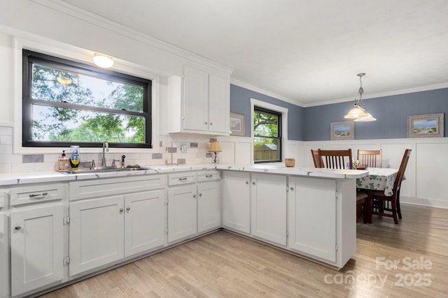 1109 S Highland Ave, Landis, NC 28088 - kitchen with a sink, light countertops, a peninsula, light wood-type flooring, and ornamental molding