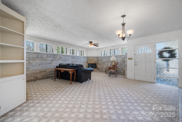 2866 Old Morganton Rd, Lenoir, NC 28645 - living area with a chandelier, a ceiling fan, a stone fireplace, carpet floors, and a textured ceiling