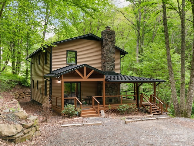 306 Mashstomp Rd, Maggie Valley, NC 28751 - view of front of property featuring faux log siding, a chimney, a porch, metal roof, and a forest view