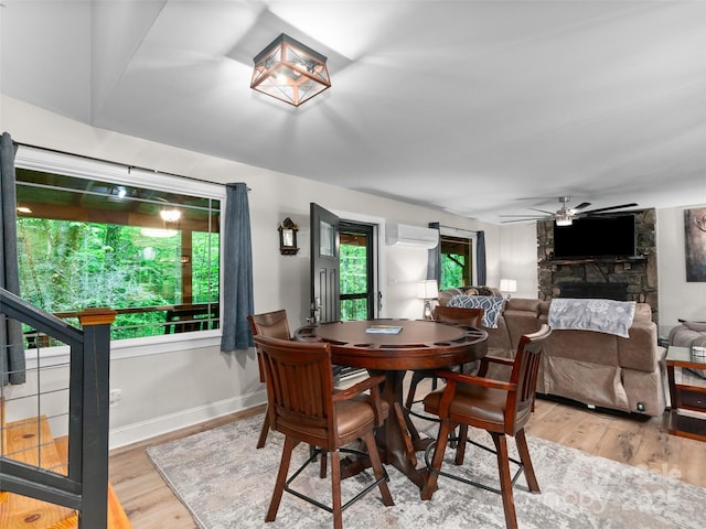 306 Mashstomp Rd, Maggie Valley, NC 28751 - dining area with a fireplace, light wood finished floors, a wall mounted air conditioner, and a ceiling fan