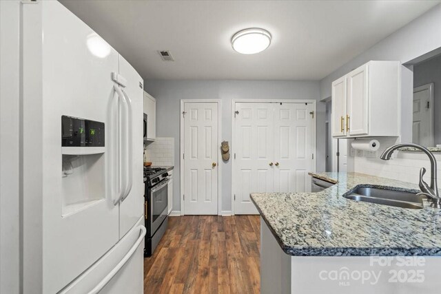 1410 Swaying Branch Ln, Clover, SC 29710 - kitchen featuring white fridge with ice dispenser, stainless steel range with gas stovetop, a sink, light stone counters, and backsplash