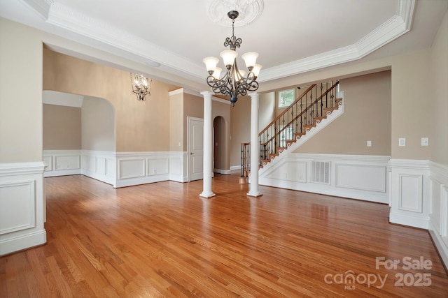 100 Woodwinds Dr, Mount Holly, NC 28120 - unfurnished living room featuring a chandelier, arched walkways, ornamental molding, a wainscoted wall, and light wood-style flooring