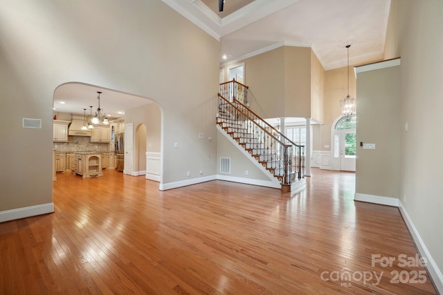 100 Woodwinds Dr, Mount Holly, NC 28120 - unfurnished living room with a towering ceiling, a chandelier, arched walkways, light wood-style flooring, and stairway
