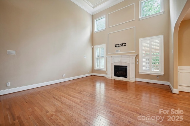 100 Woodwinds Dr, Mount Holly, NC 28120 - unfurnished living room featuring crown molding, light wood-style flooring, arched walkways, a tiled fireplace, and a high ceiling