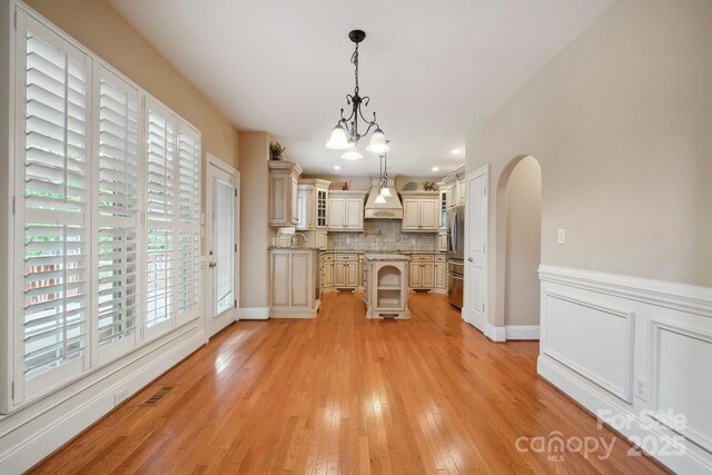 100 Woodwinds Dr, Mount Holly, NC 28120 - kitchen featuring stainless steel fridge, tasteful backsplash, a kitchen island, custom exhaust hood, and glass insert cabinets
