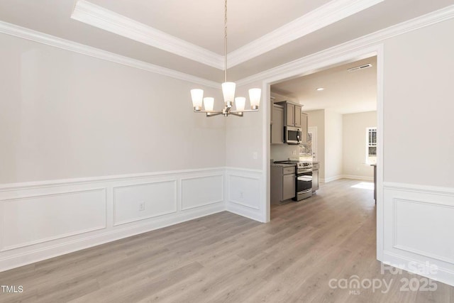 236 Mountain Island Rd Unit 40, Statesville, NC 28677 - unfurnished dining area with a chandelier, light wood-style floors, wainscoting, ornamental molding, and a decorative wall