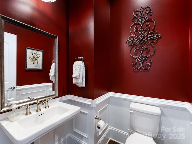 5030 Waldron Meadow Dr, Charlotte, NC 28226 - half bath featuring wainscoting, a sink, toilet, and a decorative wall