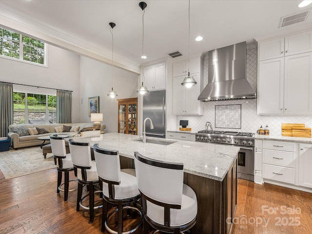 5030 Waldron Meadow Dr, Charlotte, NC 28226 - kitchen with wall chimney range hood, premium appliances, a sink, decorative backsplash, and a kitchen breakfast bar
