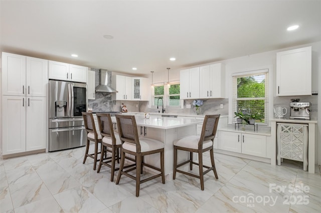 2320 Doster Rd, Monroe, NC 28112 - kitchen featuring stainless steel fridge with ice dispenser, wall chimney exhaust hood, light countertops, a kitchen breakfast bar, and light marble finish flooring
