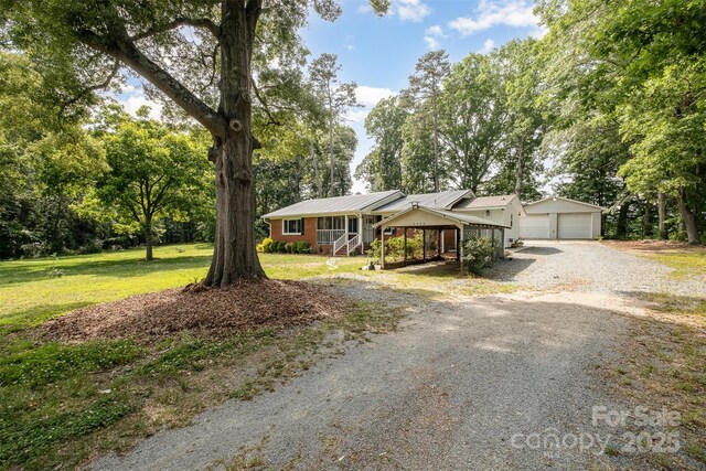 2320 Doster Rd, Monroe, NC 28112 - ranch-style house featuring a garage, a front yard, metal roof, and view of wooded area