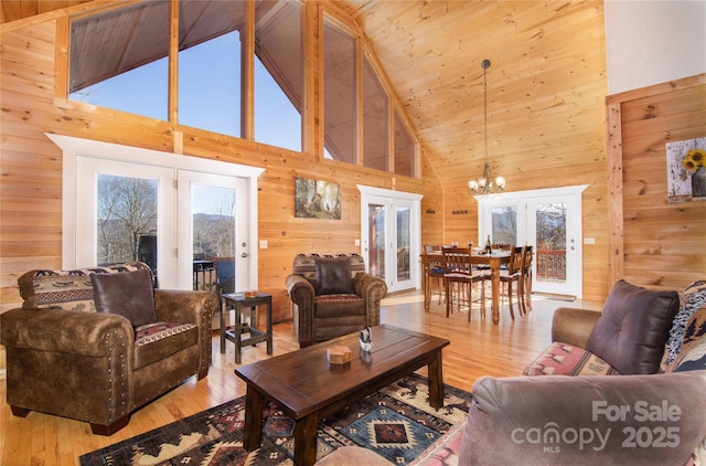 693 Blackberry Ridge Rd, Burnsville, NC 28714 - living room featuring french doors, wood walls, a chandelier, high vaulted ceiling, and hardwood / wood-style floors