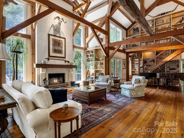 1360 Skunk Hollow Rd, Campobello, SC 29322 - living area featuring hardwood / wood-style floors, beam ceiling, high vaulted ceiling, a lit fireplace, and stairs