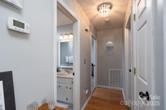 103 Poplar Trl, Rockwell, NC 28138 - hallway featuring light wood-style flooring, a sink, a textured ceiling, and baseboards