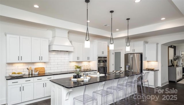411 Newstyle Way, Gastonia, NC 28056 - kitchen featuring appliances with stainless steel finishes, premium range hood, dark countertops, recessed lighting, and a breakfast bar