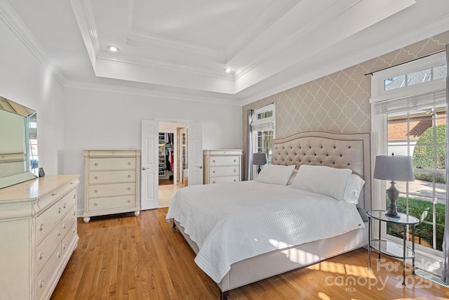 3506 Cardiff Ln, Matthews, NC 28104 - bedroom with a walk in closet, light wood-style floors, an accent wall, wallpapered walls, and crown molding