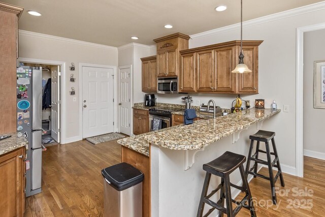 33 Stone House Rd, Arden, NC 28704 - kitchen featuring appliances with stainless steel finishes, brown cabinetry, light wood finished floors, a kitchen breakfast bar, and ornamental molding