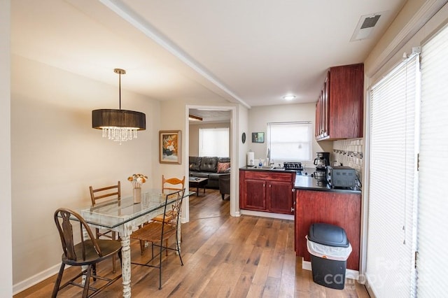 5430 Ela Rd, Whittier, NC 28789 - kitchen with reddish brown cabinets, dark countertops, a chandelier, dark wood-style floors, and decorative light fixtures