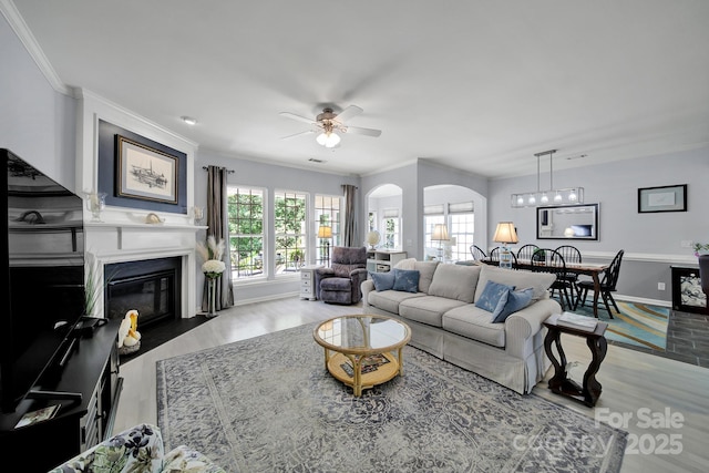 2224 Hartwell Ln, Fort Mill, SC 29707 - living room with arched walkways, wood finished floors, a ceiling fan, a glass covered fireplace, and ornamental molding
