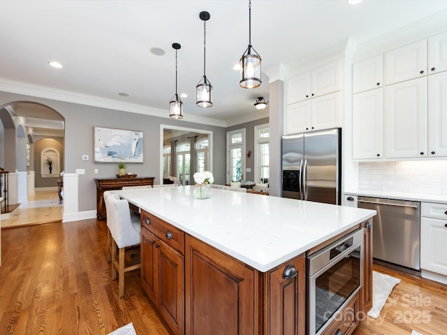 1509 Churchill Downs Dr, Waxhaw, NC 28173 - kitchen with stainless steel appliances, arched walkways, light countertops, a center island, and crown molding